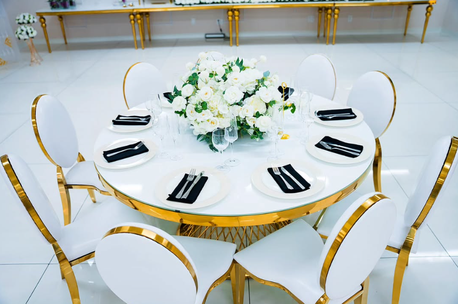 A round table with white plates and black napkins and a vase of flowers on it.