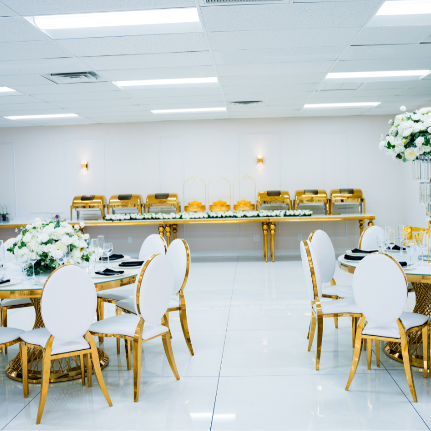 A large room with tables and chairs set up for a wedding reception