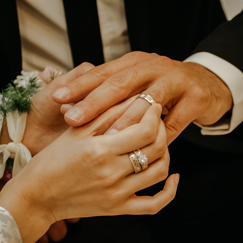 A bride and groom hold hands with their wedding rings on